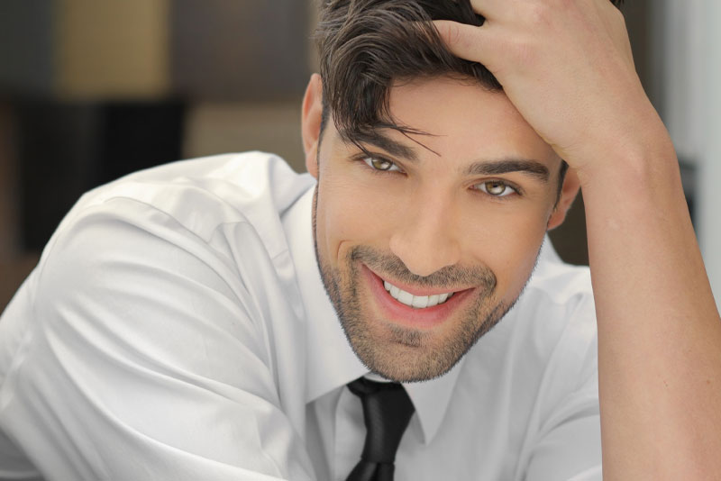 man smiling with his hand in his hair